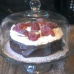 image of flourless chocolate cake with ganache, whipped cream and strawberries