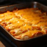 an image of cheesy chicken enchiladas in a baking pan, hot out of the oven.